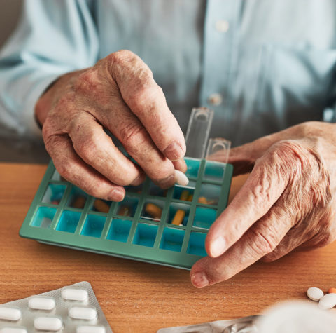 senior-man-organizing-his-medication-into-pill-dis-1600x1439
